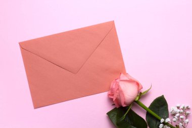 Pembe arka planda bir zarf ve güllerin kompozisyonu, yakın plan. Düğün tasarımı, selamlar, davetiyeler, duvar kağıtları.