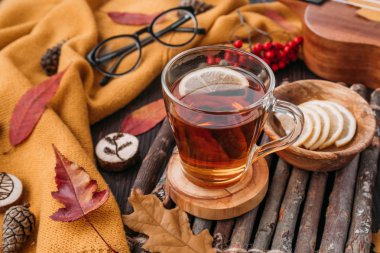 Düz yatıyordu. Desenli eşarp çay ile. Sonbahar yaprakları ahşap arka plan üzerinde. Sonbahar ya da kış konsepti.