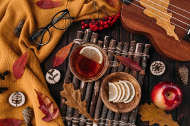 Düz yatıyordu. Desenli eşarp çay ile. Sonbahar yaprakları ahşap arka plan üzerinde. Sonbahar ya da kış konsepti.