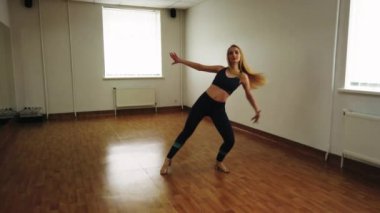 Dans stüdyosunda prova sırasında zarif çekici kadın dansçı doğaçlama çağdaş bir tarzda dans. Pürüzsüz zarif dans performans neşeli yaratıcı kadın kapalı eğitim sınıf sırasında hareket eder..