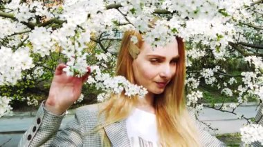 Güzellik genç kadın bahardoğa zevk , Çiçek açan ağaçları ile Bahçe Happy Beautiful kız. El gimbal tarafından yavaş çekim video çekimi