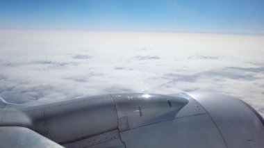 Bir yolcu görünümü bir uçağın pencereden dışarı bakıyor bulutlar rağmen uçan. Kanat kısmen görülebilir. 4k çekim