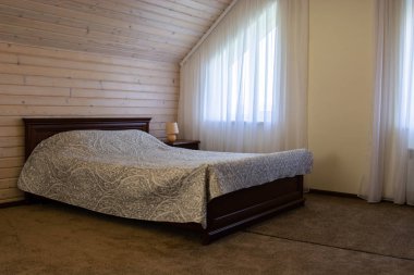 Tahta duvarın yanında yatağı olan güzel bir çatı katı yatak odası.