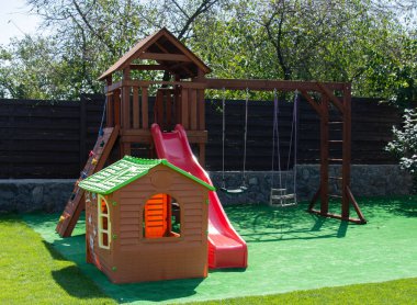 Çocuklar merdivenlerden kayıyor. Bahçedeki Woodern çocuk parkı
