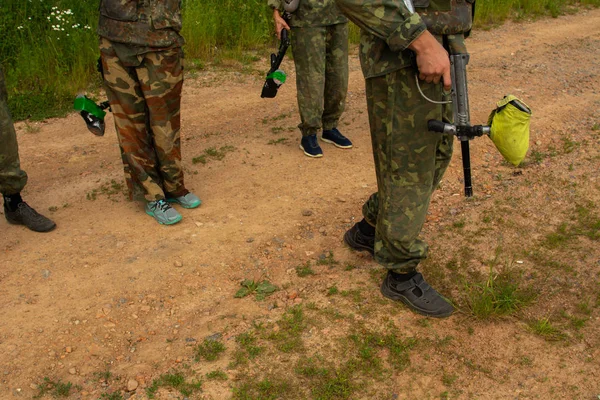 Paintball jugador deportivo con máscara protectora apuntando arma y derribado con salpicaduras de pintura en verano — Foto de Stock