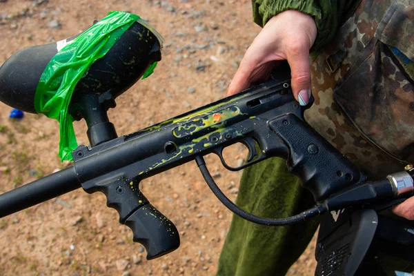 Paintball jugador deportivo con máscara protectora apuntando arma y derribado con salpicaduras de pintura en verano — Foto de Stock