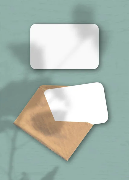 Egy Boríték Két Lap Texturált Fehér Papírral Zöld Háttéren Mockup — Stock Fotó