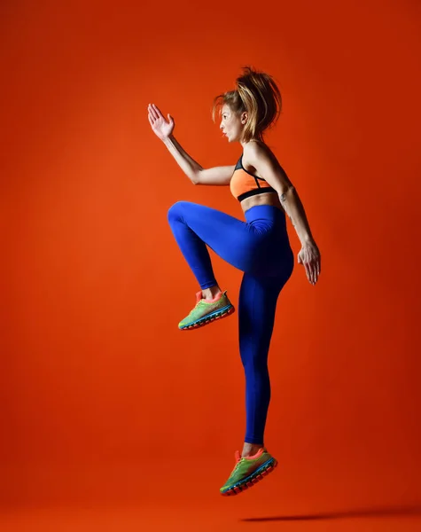 Mujer deportiva saltando. Foto de entrenamiento modelo fitness sobre fondo rojo anaranjado . —  Fotos de Stock