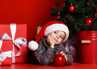 Noel Baba Noel ağacı arka plan üzerinde kırmızı şapka yatan içinde komik gülen çocuk