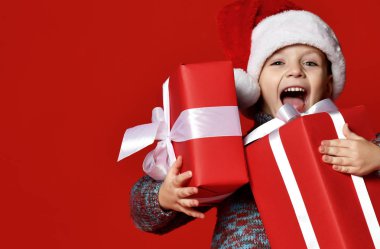 komik gülen çocuk Noel hediyesi elinde tutan Santa kırmızı şapkalı.