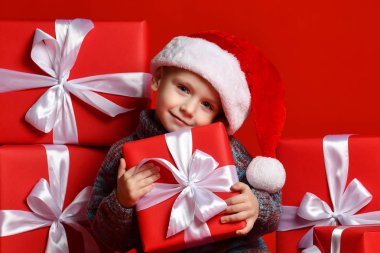 Noel Baba 'nın kırmızı şapkalı komik çocuğu elinde Noel hediyesini tutuyor. Noel konsepti.