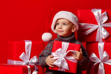 Noel Baba 'nın kırmızı şapkalı komik çocuğu elinde Noel hediyesini tutuyor. Noel konsepti.