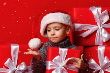 Noel Baba 'nın kırmızı şapkalı komik çocuğu elinde Noel hediyesini tutuyor. Noel konsepti.