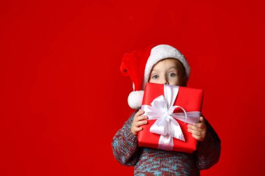 komik gülen çocuk Noel hediyesi elinde tutan Santa kırmızı şapkalı.