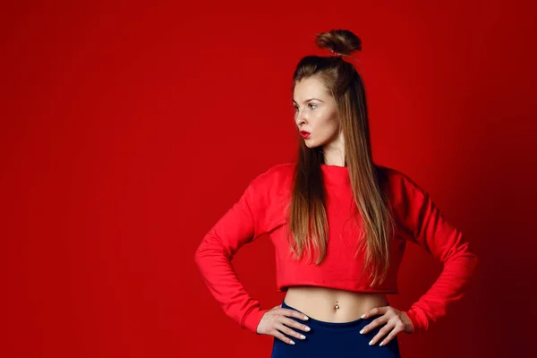 Fitness kadın spor giyim ayakta eller izole kırmızı arka plan üzerinde kalça ile — Stok fotoğraf