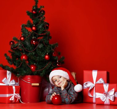 Noel Baba Noel ağacı arka plan üzerinde kırmızı şapka yatan içinde komik gülen çocuk