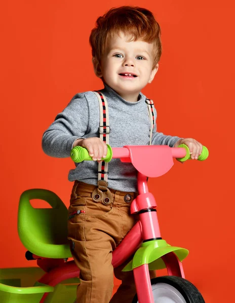 红发宝贝男孩骑自行车在一个孤立的橙色背景 — 图库照片