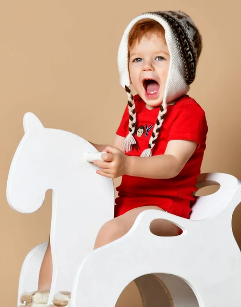 小微笑的婴儿坐在一匹白马，木制摇椅 — 图库照片