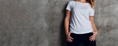 bir beyaz boş t-shirt arka plan beton duvara karşı poz içinde çekici genç kadın giyinmiş
