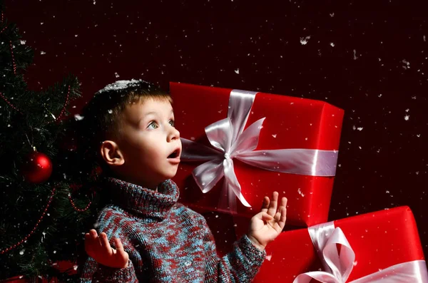 Menino na véspera do ano novo e Natal está sentado debaixo da árvore — Fotografia de Stock