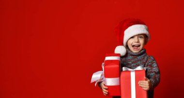 komik gülen çocuk Noel hediyesi elinde tutan Santa kırmızı şapkalı.