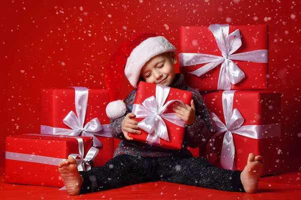Smiling funny child in Santa red hat holding Christmas gift in hand. Christmas concept. — Stock Photo, Image