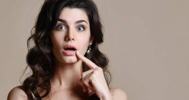 Sürpriz çok korkmuş kadın jestlerle belirsizlik, bej renkli arka plan üzerinde izole kamera bakıyor.