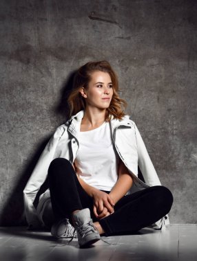 Kız beyaz duvarının yakınında. hipster kadın moda yere oturur.