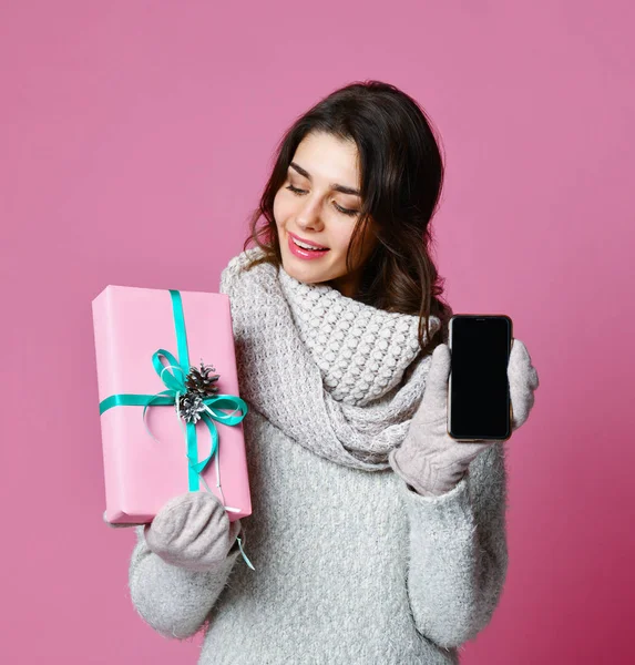 Vrouw is houden van vakken en tonen leeg scherm mobiele telefoon geïsoleerd op roze achtergrond — Stockfoto