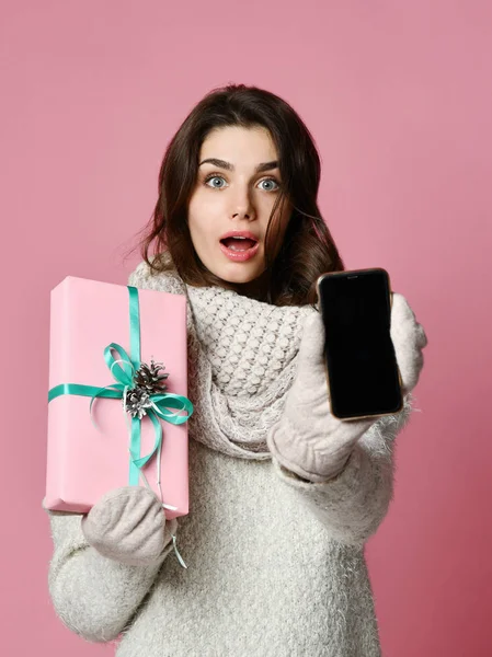 Vrouw is houden van vakken en tonen leeg scherm mobiele telefoon geïsoleerd op roze achtergrond — Stockfoto