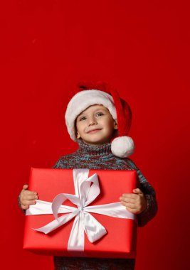 komik gülen çocuk Noel hediyesi elinde tutan Santa kırmızı şapkalı.