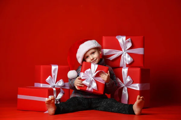 Smiling funny child in Santa red hat holding Christmas gift in hand. Christmas concept. — Stock Photo, Image