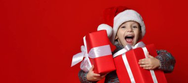 komik gülen çocuk Noel hediyesi elinde tutan Santa kırmızı şapkalı.
