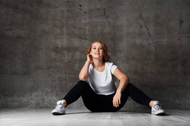 Sarı saçlı beyaz gömlek ve katta oturan siyah yırtık kot giyen Studio poz ile korku veren kadın