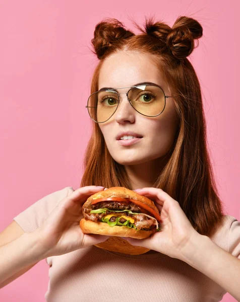 Şık ve Genç kız burger, pembe arka plan tutan güneş gözlüğü. — Stok fotoğraf