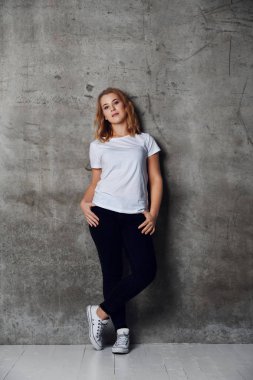 bir beyaz boş t-shirt arka plan beton duvara karşı poz içinde çekici genç kadın giyinmiş