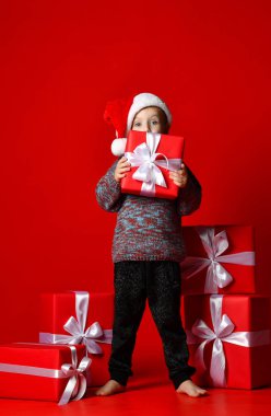 komik gülen çocuk Noel hediyesi elinde tutan Santa kırmızı şapkalı.