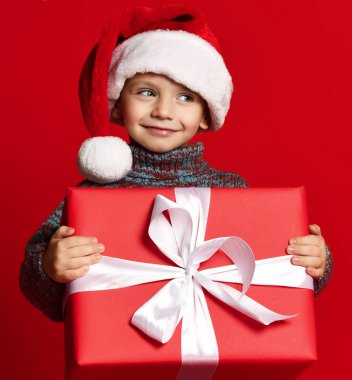Noel Baba 'nın kırmızı şapkalı komik çocuğu elinde Noel hediyesini tutuyor. Noel konsepti.