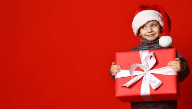 Noel Baba 'nın kırmızı şapkalı komik çocuğu elinde Noel hediyesini tutuyor. Noel konsepti.