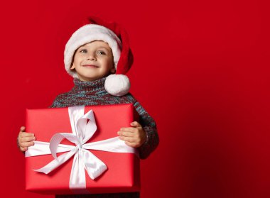 Noel Baba 'nın kırmızı şapkalı komik çocuğu elinde Noel hediyesini tutuyor. Noel konsepti.
