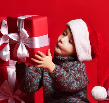 Noel Baba 'nın kırmızı şapkalı komik çocuğu elinde Noel hediyesini tutuyor. Noel konsepti.