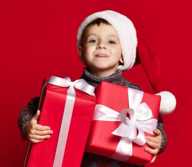 Noel Baba 'nın kırmızı şapkalı komik çocuğu elinde Noel hediyesini tutuyor. Noel konsepti.
