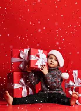 Noel Baba 'nın kırmızı şapkalı komik çocuğu elinde Noel hediyesini tutuyor. Noel konsepti.