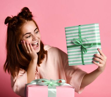 Hediye kutusu tutarak ve bu renk pembe arka plan üzerinde izole bakarak çok gülümseyen bir kızıl saçlı kız portresi