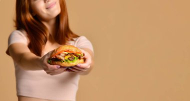Portre aç genç bir kadının çıplak arka plan üzerinde izole hamburger yeme kapatmak