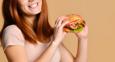 Portre aç genç bir kadının çıplak arka plan üzerinde izole hamburger yeme kapatmak