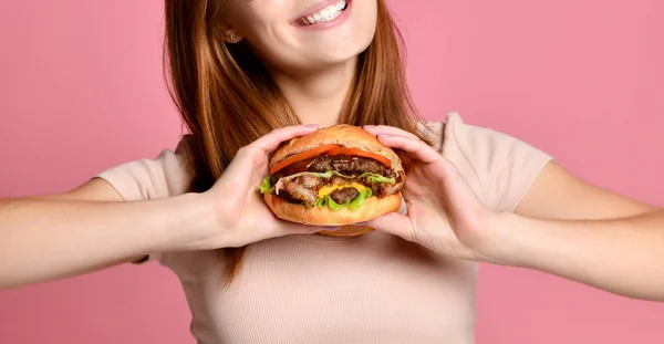 Gros plan portrait d'une jeune femme affamée mangeant un hamburger isolé sur fond rose — Photo