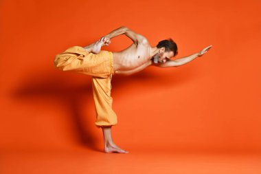 Turuncu arka planı germe yapıyor yaşlı adam pratik yoga egzersizleri