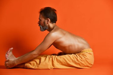 Yaşlı adam Ashtanga Vinyasa yogası yapıyor geriye doğru eğilerek asana Paschimottanasana - öne doğru eğiliyor.