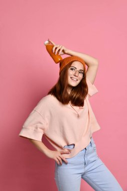 Taze portakal suyu şişeden, içme bardaklarda kıvırcık saçlı Genç hipster kadın zevk açık havada ile vakit.